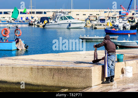 Bateaux de pêche dans le vieux port de Bari sur la côte Adriatique, région des Pouilles, en Italie. Pêcheur prépare pour la cuisson du poulpe dans lungomare marché. Banque D'Images