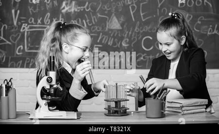 Expérience Pédagogique concept. Microscope et de tubes à essai sur table. Attention l'exécution de la réaction chimique. Connaissances de base en chimie. Les filles étudient la chimie. Faire en chimie intéressant. Banque D'Images