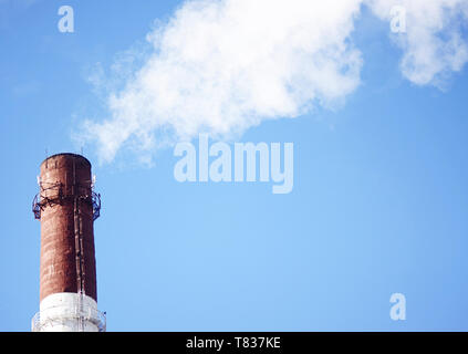 Tuyau d'usine émettant des gaz d'échappement dans le ciel bleu clair, qui polluent la nature Banque D'Images