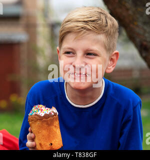 Young boy rit parce qu'il a enduit tout en mangeant un petit gâteau Banque D'Images