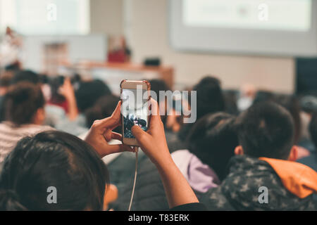 Vue arrière du girl taking photo de peaople en utilisant le téléphone mobile. Visible de l'écran du smartphone Banque D'Images