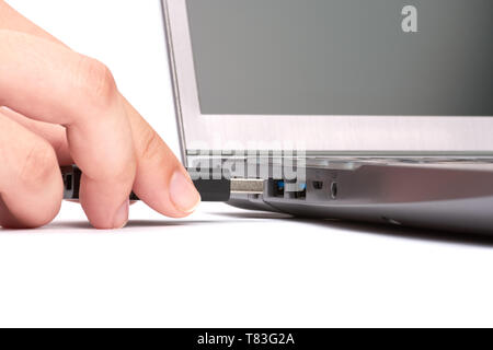 La main d'une jeune femme se connecte un lecteur flash USB à un port dans un ordinateur portable avec un clavier noir. Isolé sur fond blanc. Banque D'Images