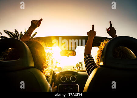 Les gens heureux pour les voyages vacances en voiture décapotable d'abandonner les mains et danse pour la mer des vacances locations - soleil sur l'horizon et joyeux Banque D'Images