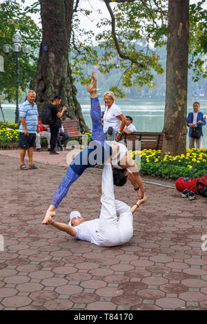 Un jeune couple d'effectuer des acrobaties sur le trottoir sur le côté de Lac Hoan Kiem, dans le centre historique de Hanoi, Vietnam du Nord, Asie du sud-est Banque D'Images