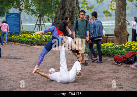 Un jeune couple d'effectuer des acrobaties sur le trottoir sur le côté de Lac Hoan Kiem, dans le centre historique de Hanoi, Vietnam du Nord, Asie du sud-est Banque D'Images