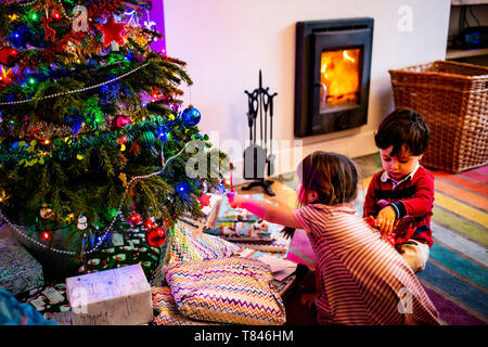 Fille et femme toddler playing par arbre de Noël de salon Banque D'Images