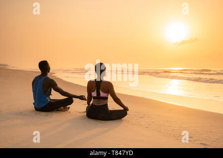 Couple practicing yoga on beach Banque D'Images