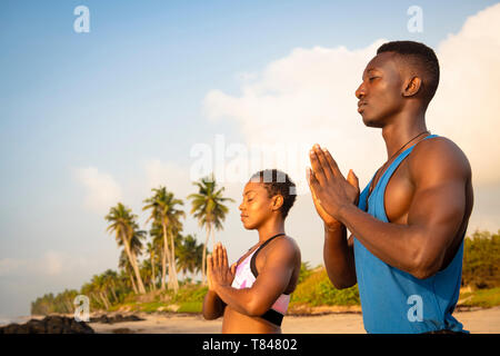 Couple practicing yoga on beach Banque D'Images