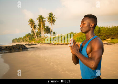 Man practicing yoga on beach Banque D'Images