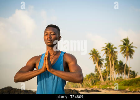 Man practicing yoga on beach Banque D'Images