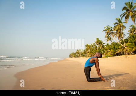 Man practicing yoga on beach Banque D'Images