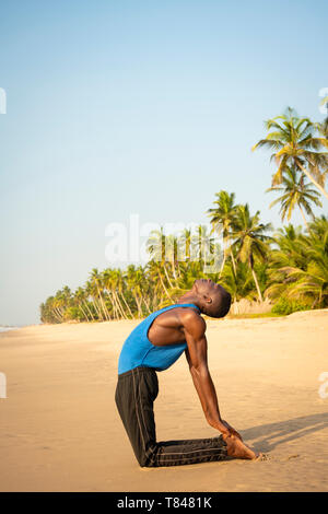 Man practicing yoga on beach Banque D'Images