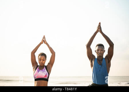 Couple practicing yoga on beach Banque D'Images