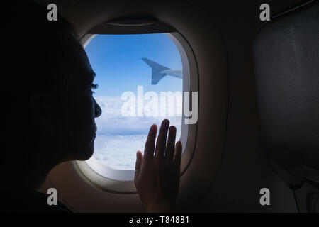 Femme voyageant en avion, looking out window Banque D'Images