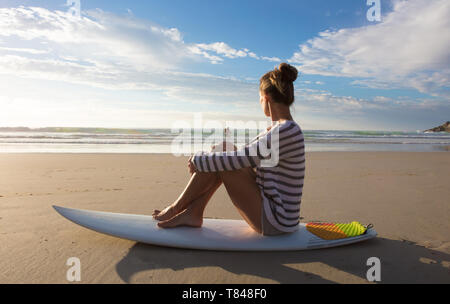 Femme assise sur surfer with surfboard on Beach, Cape Town, Western Cape, Afrique du Sud Banque D'Images