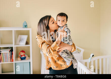 Mère embrassant bébé fils en pépinière, portrait Banque D'Images