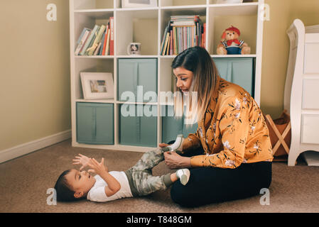 Mother sitting sur les jardins d'étage mettre des chaussettes bébé Banque D'Images