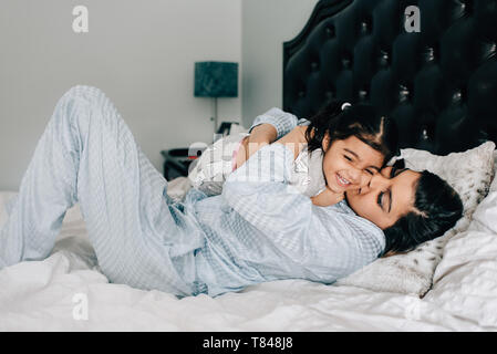 Fille et mère hugging on lit dans la matin Banque D'Images