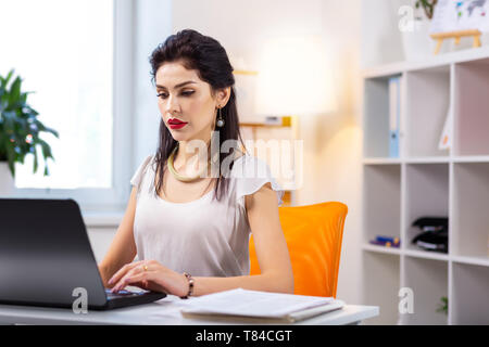 Appel à poil long dame en blanc top working on laptop Banque D'Images