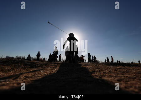 Beijing, Chine. Le 11 mai, 2019. Un manifestant palestinien utilise une fronde pour lancer des pierres sur des soldats israéliens lors d'affrontements sur la frontière Gaza-Israel, est de la ville de Gaza, le 10 mai 2019. Source : Xinhua/Alamy Live News Banque D'Images