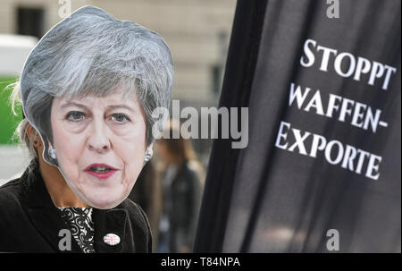 Berlin, Allemagne. Le 11 mai, 2019. Un militant avec un masque par Theresa May, Premier ministre de Grande-Bretagne, se dresse en face de la porte de Brandebourg à l'occasion d'une action de la 'Aktion Aufschrei - Stoppt den Waffenhandel ! Ils protestent contre les exportations d'armes à la guerre-participants au Yémen sur un trône d'armes' sur le modèle du "Trône de fer" de jeux de trônes. Credit : Jens Kalaene Zentralbild-/dpa/dpa/Alamy Live News Banque D'Images