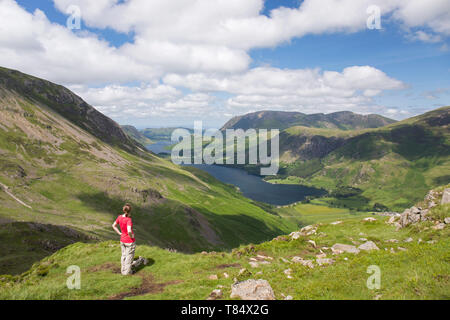 Parc National de Lake District, Cumbria, Angleterre. Girl admiring view plus de Buttermere et lointain de Crummock Water les pentes ouest des meules. Banque D'Images