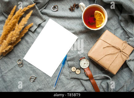 Belle tasse de thé au citron, et cértificat de différents accessoires sur fond tricoté gris . Automne-hiver confortable concept. Banque D'Images