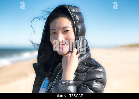 Une femme chinoise smiling en dehors par un jour de vent sur le Cape Cod National Seashore, au Massachusetts. Banque D'Images