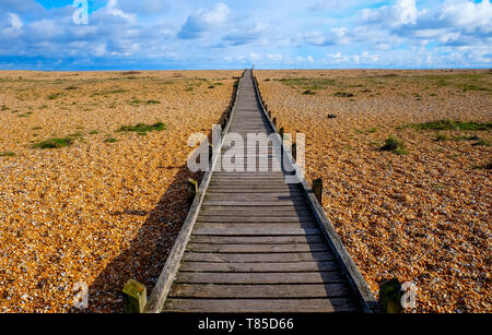 Une longue ligne droite decking en bois avec un diminshing point de vue sur une plage de galets, le chemin commence à l'avant-plan grand centre de l'image Banque D'Images