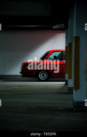 Oldtimer rouge voiture dans un parking abandonné Banque D'Images