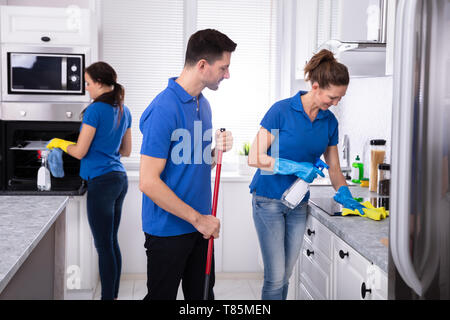 Groupe de jeunes portiers en uniforme à la maison Cuisine Nettoyage Banque D'Images