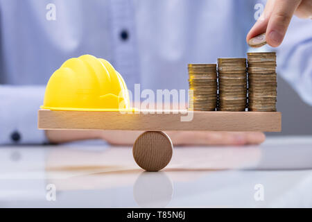 Placer la main Coin en haut de la pile de monnaie et casque jaune Banque D'Images