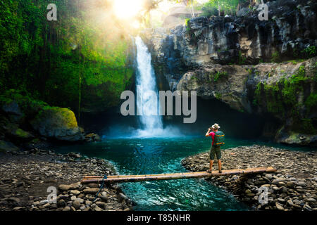 Photographe avec appareil photo en main faire photo épique amazing waterfall dans les rayons du soleil au lever du soleil sur l'incroyable fond nature paysage Banque D'Images