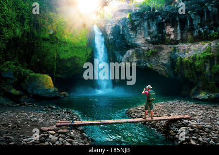 Mode de vie actif et photographe de voyage avec sac à dos de l'appareil photo la photo cachée dans cascade jungle tropicale Banque D'Images