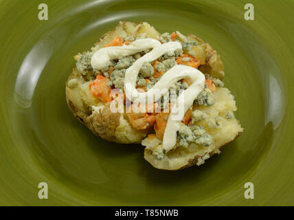 Seule portion de pomme de terre au four farcies de poulet épicé, chaud avec du fromage bleu et crème aigre sur plaque verte Banque D'Images