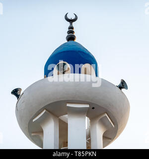 Embout peint blanc et bleu d'un minaret avec haut-parleurs et un croissant de lune bronze sur le côté. Banque D'Images