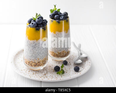 Chia vanille saine au lait dans un verre avec des bleuets frais et de menthe. Banque D'Images
