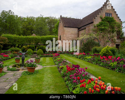 Chenies Manor jardin en contrebas avec pavillon et étang au début de mai montrant tulipes colorées, sculpture et feuillage vert frais joliment aménagé. Banque D'Images