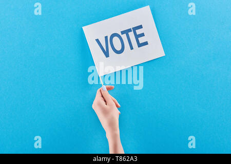 Portrait de femme tenant un drapeau blanc avec lettrage de vote dans la main sur fond bleu Banque D'Images