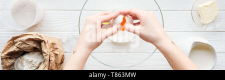 Vue panoramique shot of woman cracking egg dans un bol pendant la cuisson sur table Banque D'Images