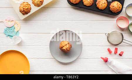 Vue de dessus de délicieux muffins dans les bacs et outils de cuisson sur table en bois Banque D'Images