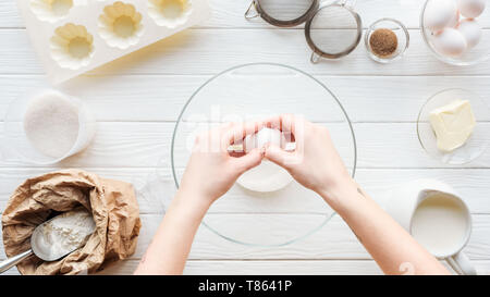 Vue partielle de la fissuration femme oeuf dans bol pendant la cuisson sur table Banque D'Images