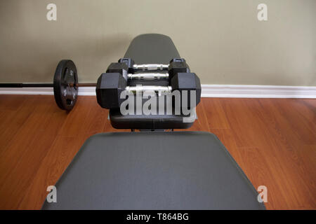 Dumbells noir de 5, 10 et 15 livres dans une rangée sur un banc Banque D'Images