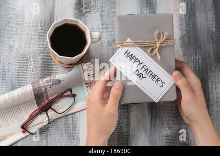 Man holding gift box avec HAPPY FATHER'S DAY card sur table Banque D'Images