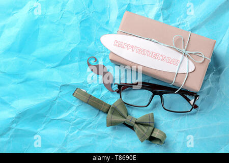 Boîte cadeau, lunettes, moustache et la sangle sur un fond de couleur. Happy Father's Day celebration Banque D'Images