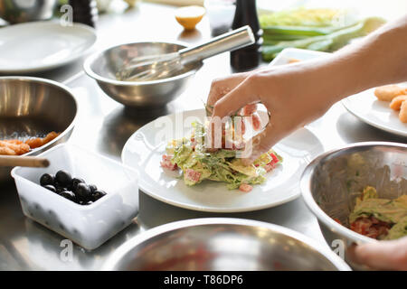 Male chef preparing salad pour servir dans une cuisine de restaurant Banque D'Images