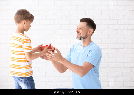 La réception de l'homme cadeau pour le jour de père de son fils sur fond clair Banque D'Images