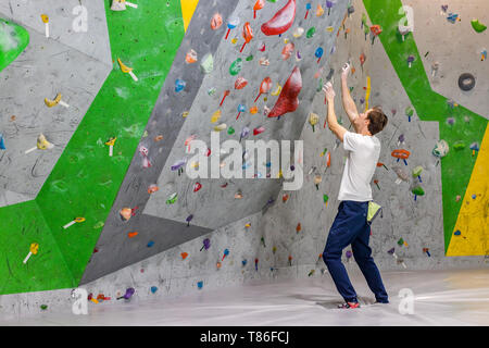 Climber explore et développe un itinéraire sur un mur d'escalade dans la salle de blocs Banque D'Images