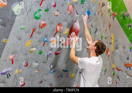 Climber explore et développe un itinéraire sur un mur d'escalade dans la salle de blocs Banque D'Images