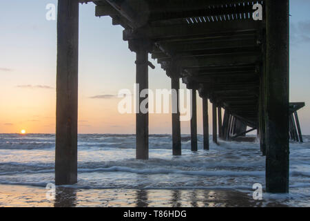 Lever du soleil au Claremont Pier avec des vagues se brisant sur la super-structure, Lowestoft Banque D'Images